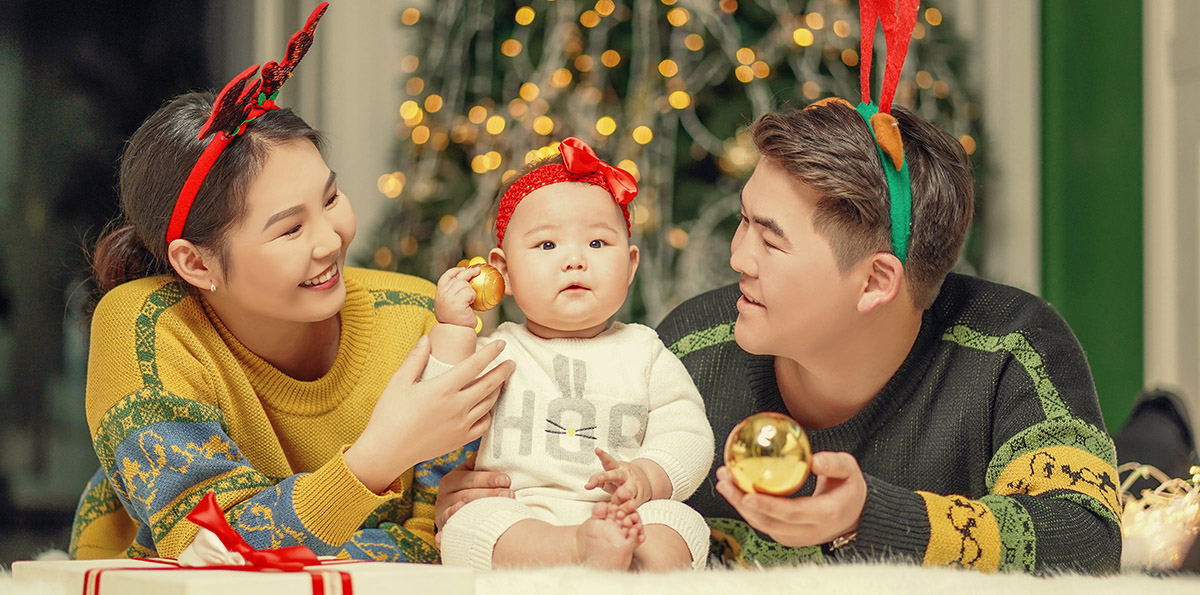 Asian family decorating for Christmas with their baby daughter