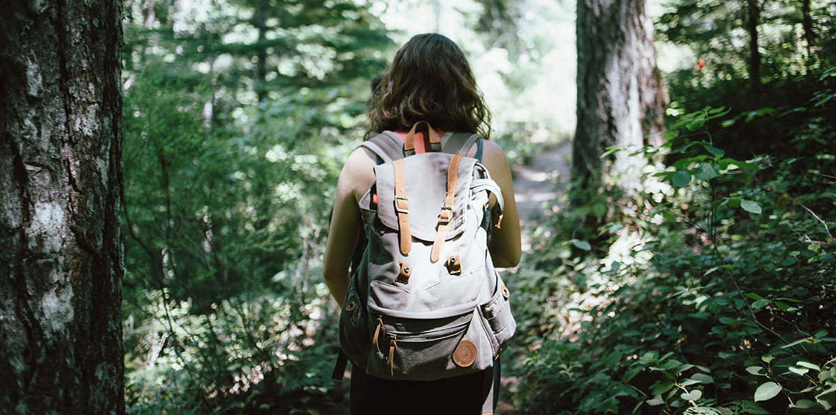 Woman hiking through the woods wearing a backpack