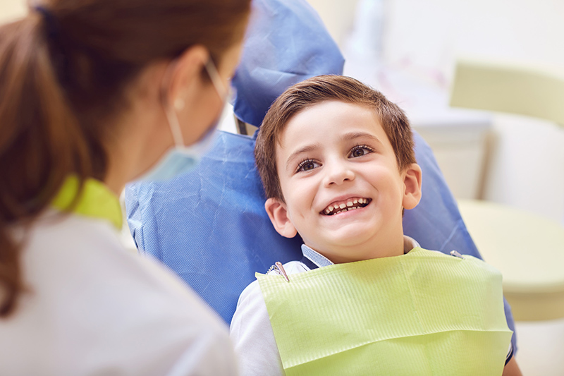 child smiling at doctor in chair for dental work