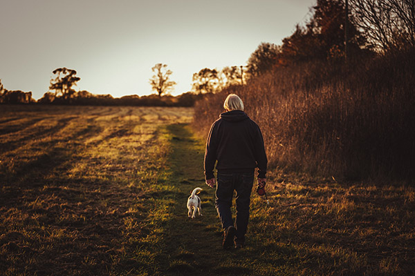 Man Walking Dog Outdoors to Get Exercise and Boost Mood | Pexels (James Frid)