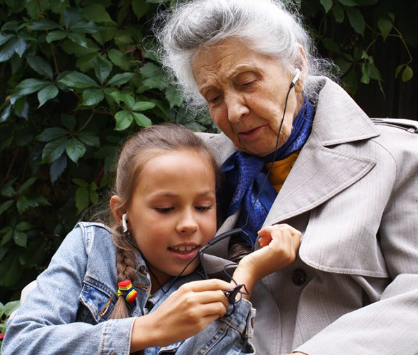 Little girl listening to music with her grandma, grandmother, child