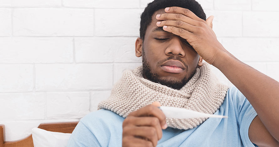 man upset with thermometer reading in bed