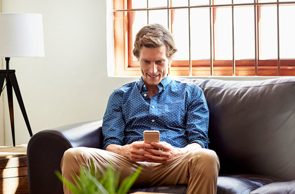 Man on couch conducts telemedicine visit with his doctor