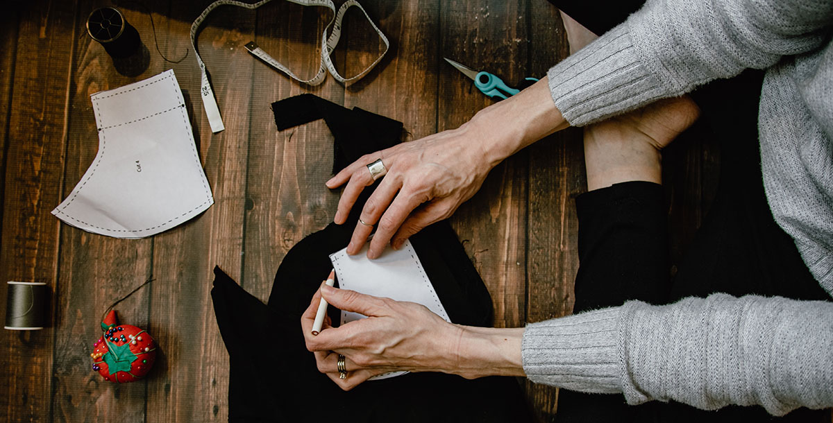 Making your own cloth mask - woman using a mask template to hand sew a mask