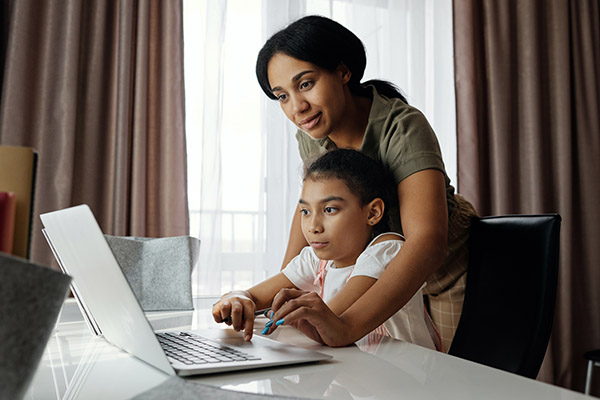 Mother helping daughter on laptop so she can do virtual learning at home