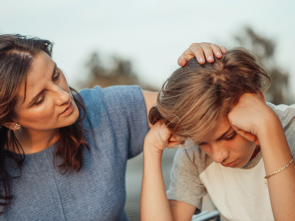 Parent talking to and comforting their frustrated, upset son