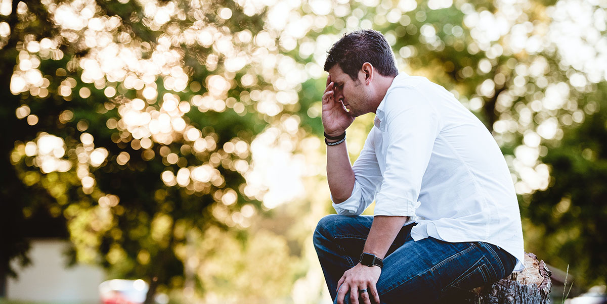 Stressed man with hand pressed to forehead | Photo by ben-white-unsplash