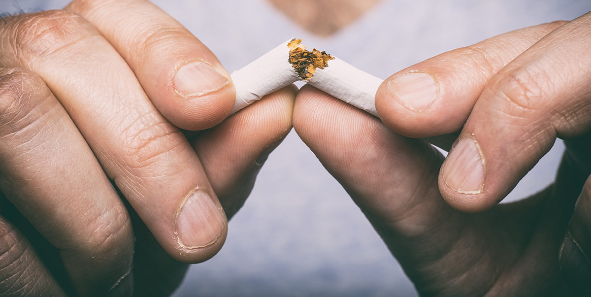 Man snapping a cigarette in half as he quits smoking tobacco