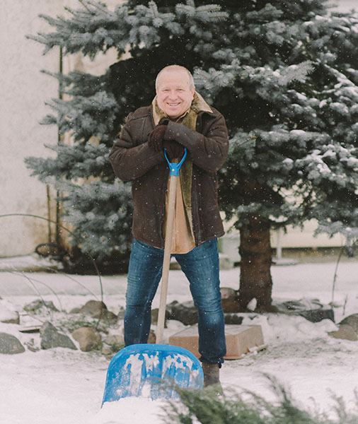 A man standing with shovel snow taking a break (Pexels)