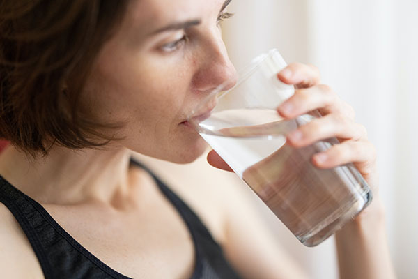 Woman drinking a glass of water (Unsplash)