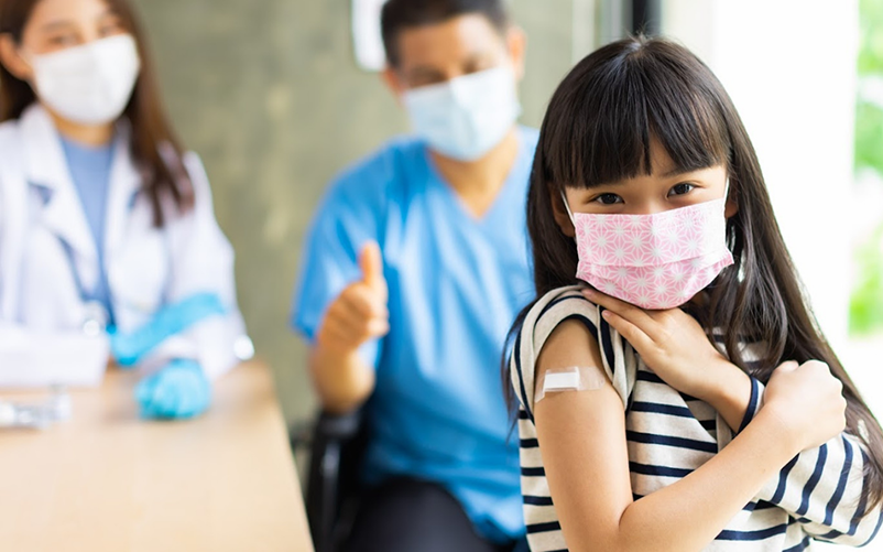 Happy young girl with band-aid after getting her vaccine