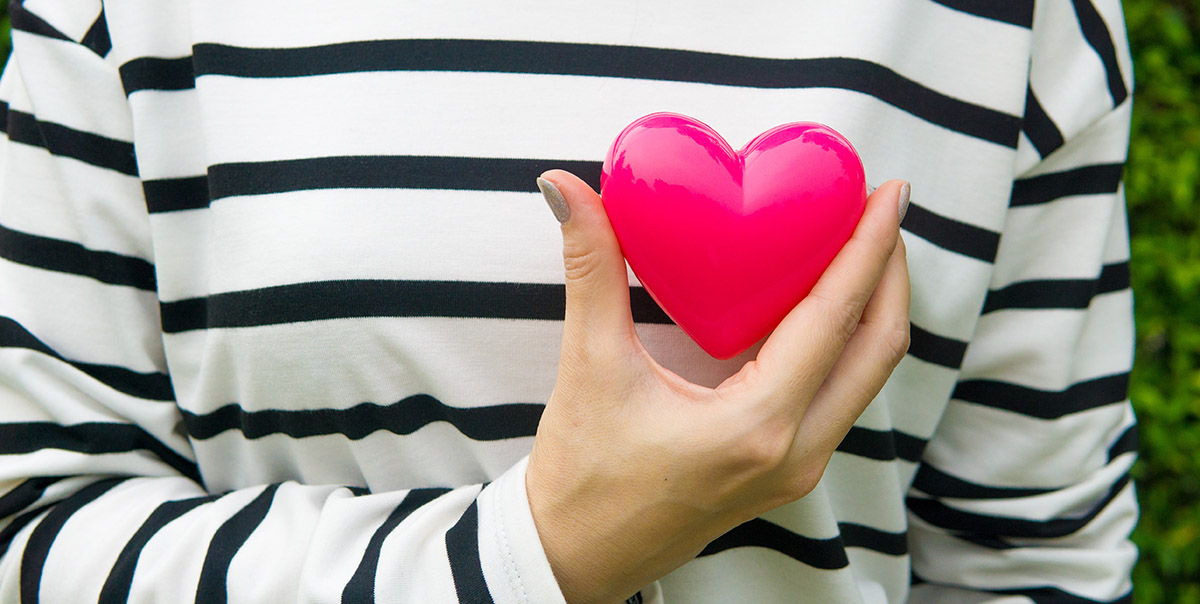 Young Woman Holding Valentine Style Pink Heart in Manicured Hand