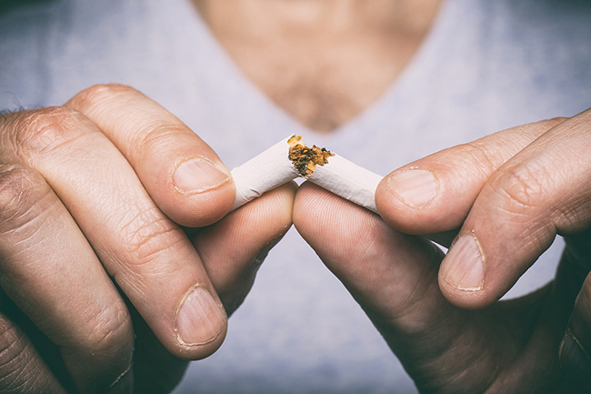 A man snapping a cigarette in half to demonstrate that he's quitting tobacco to improve his heart health