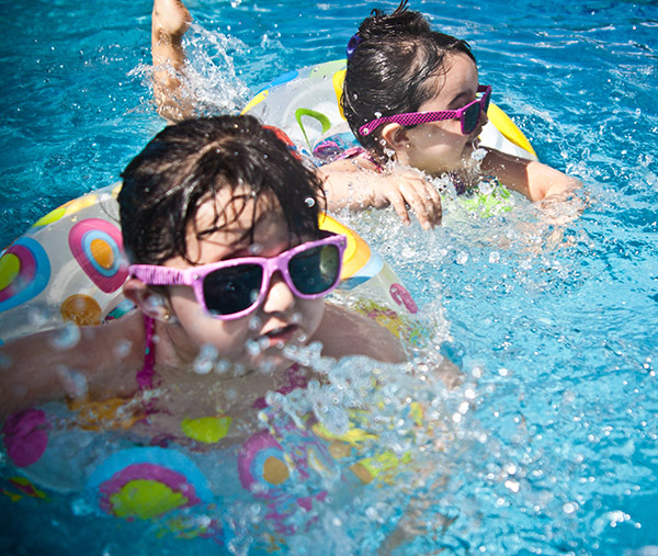 Young Girls Swimming in Sunglasses with Life Preservers; Image by Juan Salamanca