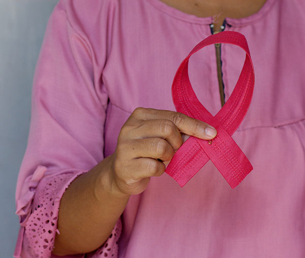 Woman dressed in pink blouse holding breast cancer awareness ribbon