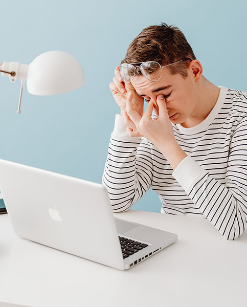 Tired man rubbing at his eyes and feeling rundown while working on his laptop