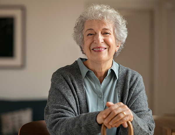 An older woman with gray hair sitting and smiling