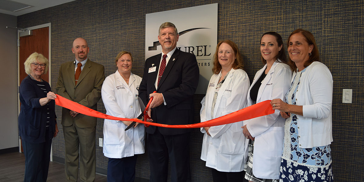 Laurel Health team cutting a red ribbon with large ceremonial scissors alongside local community leaders and legislators to commemorate the opening of the new Towanda Laurel Health Center