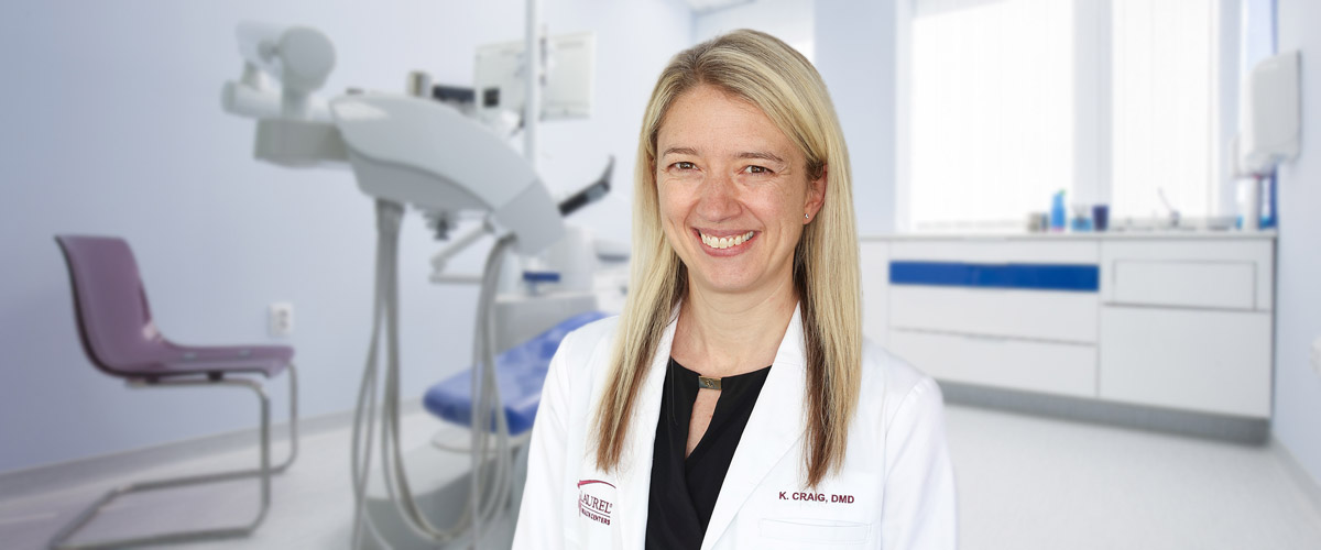 Photo of dentist Kate Craig, DMD, standing in an exam room; Dr. Craig is a dentist providing care to patients of all ages at the Sullivan County Laurel Health Center in Laporte, PA.