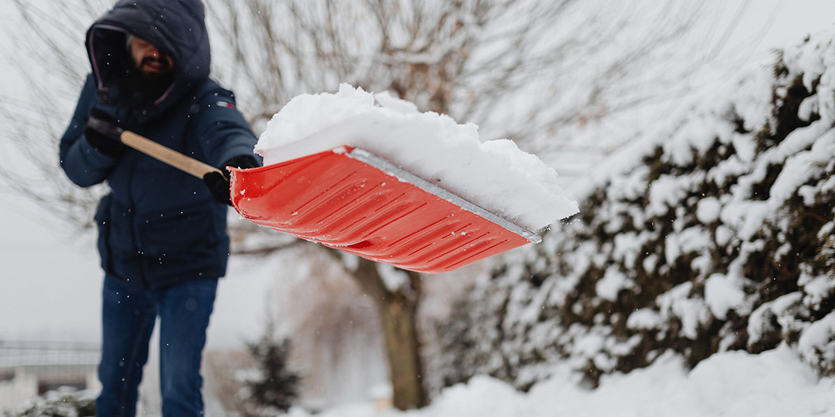 A man dressed in a heavy winter coat shoveling snow in the winter